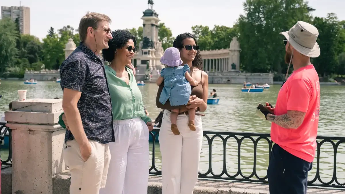 Family bike tour stop by the lake and rowboats in El Retiro Park